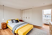 Yellow bed and fitted wardrobes in bedroom with ensuite bathroom