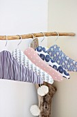 Fabric-covered coathangers on branch used as clothes rack