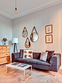 Three mirrors above grey sofa and coffee table in renovated townhouse apartment
