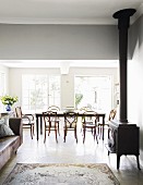 Offener Wohnbereich mit Kaminofen und Sofa, im Hintergrund Esstisch mit Stühlen vor Terrassentür