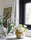 Blumen und Sukkulenten in Vasen und unter einer Glasglocke