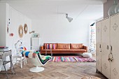 Leather couch, colourful rug and retro easy chair in living area