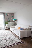 Scatter cushions in white sofa, houseplant on wooden stool and artistic table lamp