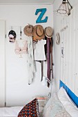 Various items of clothing and hats hung from coat pegs in bedroom