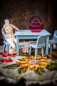 Hellblaue Puppenmöbel mit morbider, nostalgischer maskuliner Porzellanpuppe auf gestickter Decke