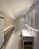 Washstand against half-height wall and frosted glass partition in modern attic bedroom