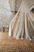 Mosquito net over bed in restored period building with Mediterranean ambiance