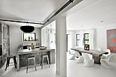 Offener Wohnraum mit Designklassikern, rustikalem Baumstammtisch und Betonküchenblock