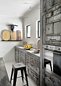 Fitted kitchen with moulded concrete frames, vintage wooden fronts and designer bar stools