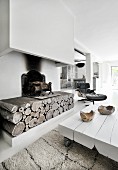 Low white coffee table in front of rustic fireplace with chimney breast