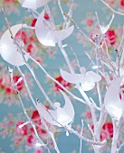 Paper angels and fairy lights hung on white-sprayed twigs