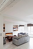 Fire in fireplace, opium table and white wooden floor in lounge of renovated period apartment