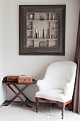 White antique armchair and side table below collection of walking-stick handles in display case