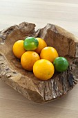 Oranges and limes in rustic wooden bowl