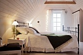 Schlafzimmer mit nostalgischem Flair und Lichterkette im Dachgeschoss