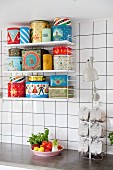 Various colourful retro tins on String shelves in whit-tiled kitchen