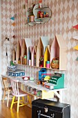 DIY play shop and house-shaped shelf units against diamond-patterned wallpaper