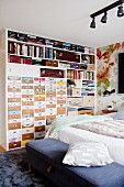 Drawers with creative fronts and crammed shelves in shelving unit in bedroom