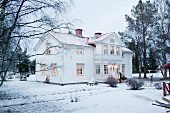 White Swedish house with illuminated windows in winter landscape
