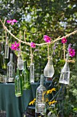 Pink cosmos in glass bottles and tealights hung from rustic cord