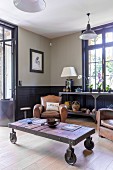 Comfortable vintage leather armchairs and rustic coffee table on castors in traditional living room