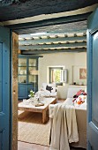 Blick durch blaue Doppeltüren ins Wohnzimmer mit Balkendecke