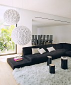 Spherical lamps above black sofa and view of dining table