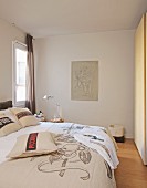 Bedspread and scatter cushions with mottos on double bed in front of Baroque drawing