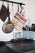 Rustic kitchen utensils hung from rod above kitchen cooker