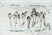 Quail eggs on old silver spoons on rustic wooden surface