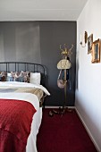 Metal bed and old coat stand against black wall