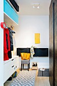 Fitted cabinets and storage boxes in hallway with small yellow inspection door on white wall