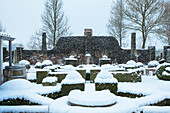 Formal gestalteter Garten im Winter, mit Buchsbaumhecken unter Schnee bedeckt