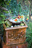Bowl of pebbles and nasturtium flowers below water spout