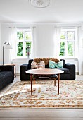 Round coffee table and black sofa in bright living room