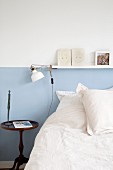 Bett vor einer Wand mit blauem Sockel und einer Bilderleiste