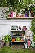 Gardening utensils, nesting boxes and plants against white board fence