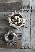 Two wreaths of feathers and quail eggs on weathered wood