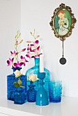 Collection of various blue vases holding orchids and rose