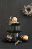 Easter arrangement of feathers and painted eggs on black cake stand