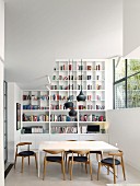 Bookcases and retro chairs in modern dining room with high ceiling