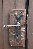 Traditional door handle wit cockerel motif on rustic brown wooden door
