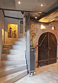 Concrete stairs leading down into cellar with arched door, niches and lighting