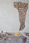 Rendered wall with section of exposed stone masonry, stone trough and candles