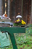 Button mushrooms on scales and wooden toadstools on arrangement of moss and flowers