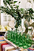 Grüne Gläser auf silbernen Tablett, bunte Tischdecke
