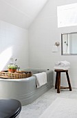 Grey bathtub with rustic accessories under sloping ceiling