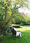 Rattan rocking chair with fur blanket under tree in garden