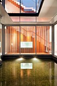 Illuminated pool in light well of modern building with view into stairwell