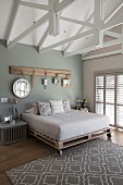 Mirrors hung from hooks on rustic wooden board in bedroom with exposed wooden roof structure